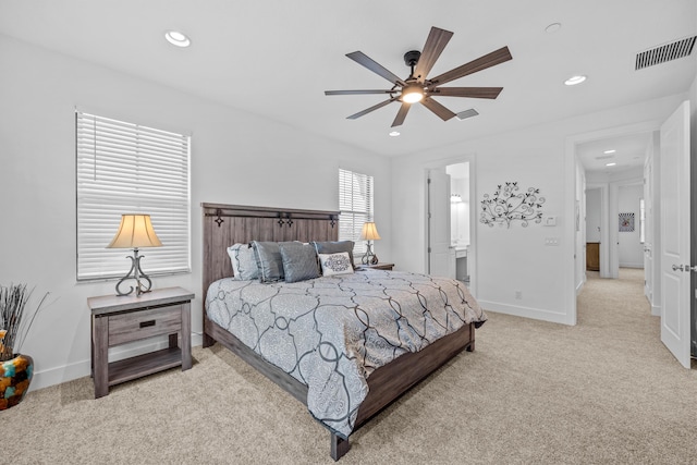 bedroom with connected bathroom, light carpet, and ceiling fan