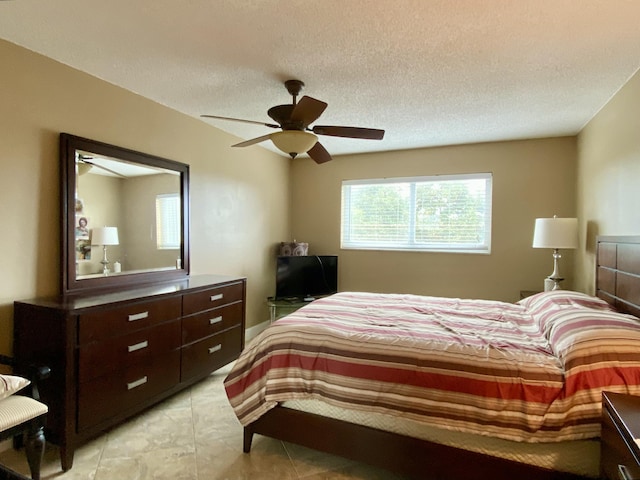 tiled bedroom with ceiling fan and a textured ceiling