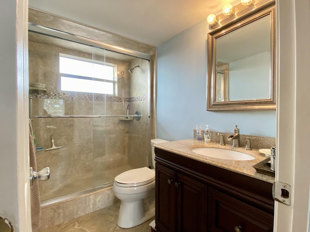 bathroom featuring vanity, a shower with shower door, and toilet