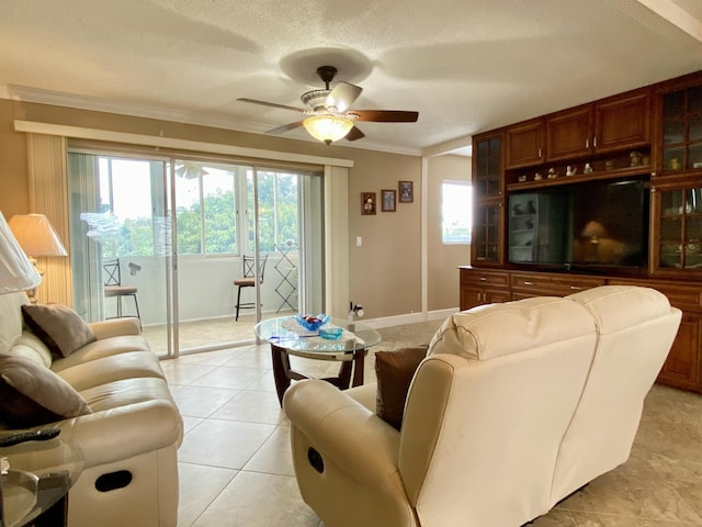 living room with light tile patterned flooring, plenty of natural light, ornamental molding, and ceiling fan