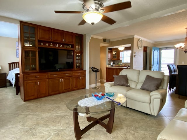 living room featuring ornamental molding and ceiling fan with notable chandelier