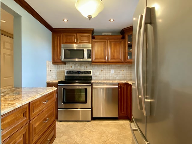 kitchen with light stone counters, stainless steel appliances, crown molding, and tasteful backsplash