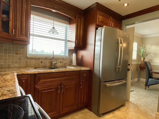 kitchen featuring sink, crown molding, stainless steel fridge, light stone counters, and tasteful backsplash