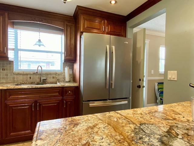 kitchen featuring pendant lighting, sink, stainless steel refrigerator, backsplash, and ornamental molding