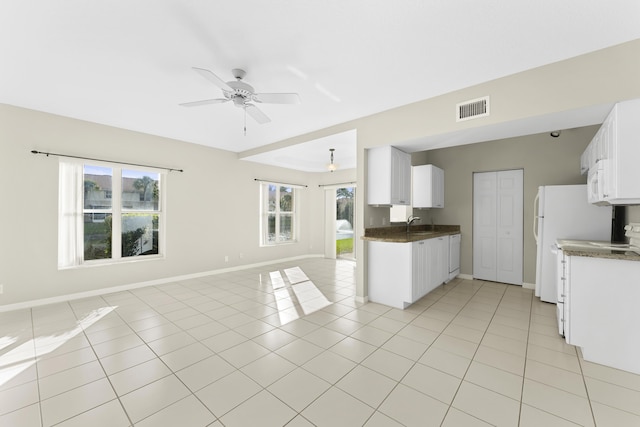 kitchen featuring sink, light tile patterned floors, white cabinets, and ceiling fan