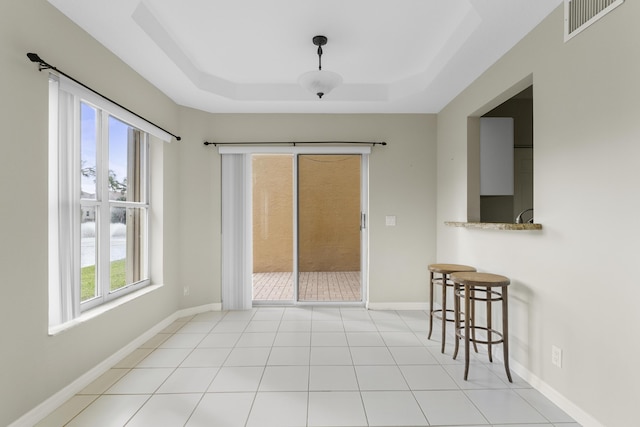 tiled empty room with a raised ceiling