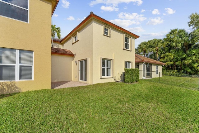 rear view of property featuring central AC unit, a lawn, and a patio