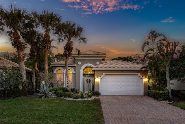 mediterranean / spanish-style house with a yard and a garage