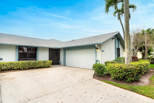 view of front of house with a garage, concrete driveway, roof with shingles, and stucco siding