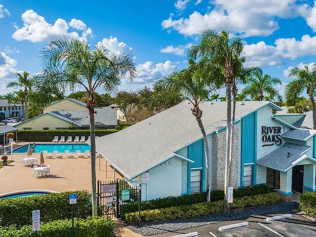 view of property with a community pool, fence, and uncovered parking