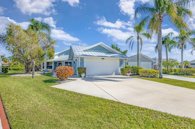 single story home with metal roof, a garage, concrete driveway, a front yard, and a standing seam roof