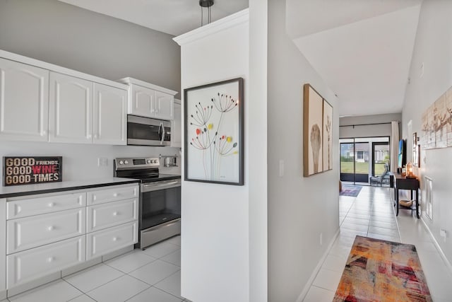 kitchen featuring hanging light fixtures, light tile patterned flooring, white cabinets, and appliances with stainless steel finishes