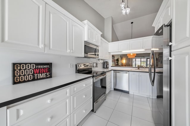 kitchen featuring light tile patterned flooring, sink, vaulted ceiling, appliances with stainless steel finishes, and white cabinets