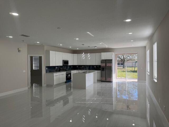 kitchen with sink, white cabinetry, a center island, stainless steel appliances, and backsplash