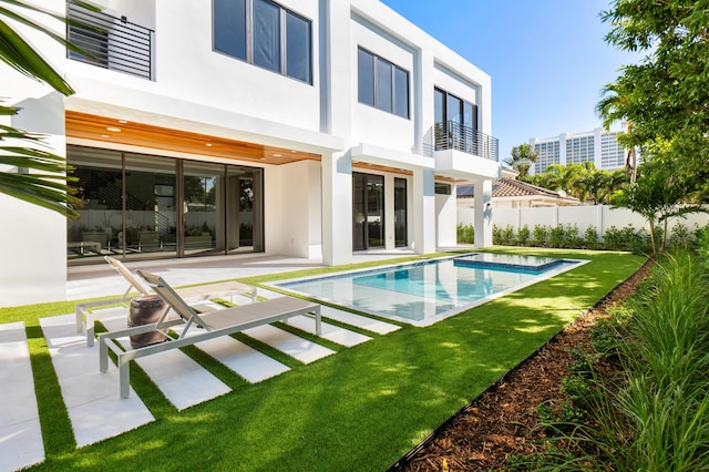 back of house featuring a balcony, a fenced in pool, and a patio area