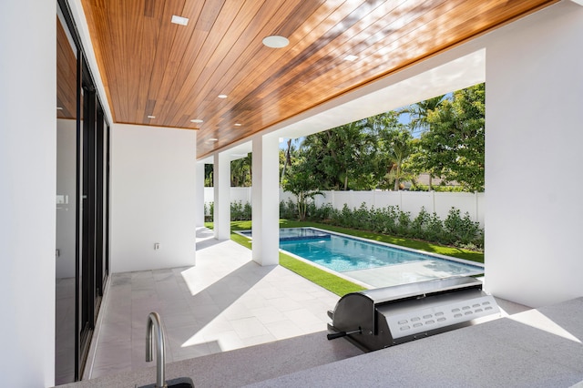 view of pool with grilling area and a patio