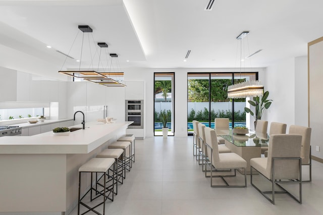 kitchen featuring sink, hanging light fixtures, a kitchen bar, a notable chandelier, and a center island with sink