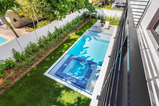 view of pool with a lawn and an in ground hot tub