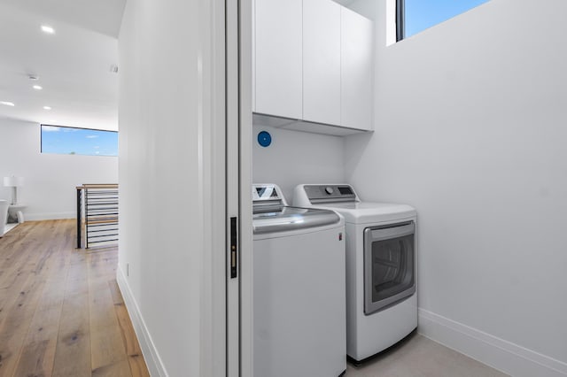 laundry area with separate washer and dryer, light hardwood / wood-style flooring, and cabinets