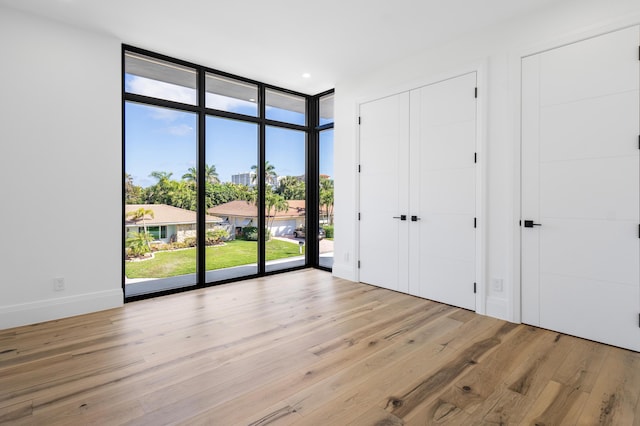 unfurnished room with expansive windows and light wood-type flooring