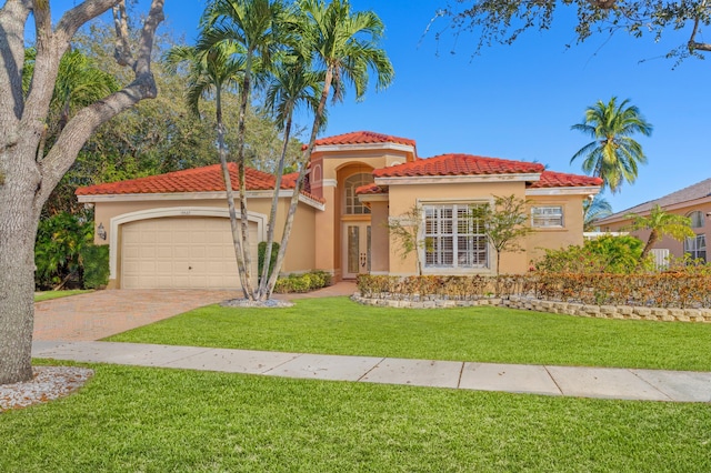 mediterranean / spanish house featuring a garage, stucco siding, a tile roof, decorative driveway, and a front yard