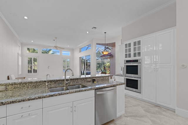 kitchen with appliances with stainless steel finishes, stone countertops, crown molding, and a sink