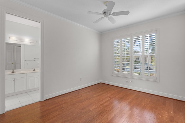 unfurnished bedroom featuring baseboards, connected bathroom, ceiling fan, hardwood / wood-style floors, and crown molding