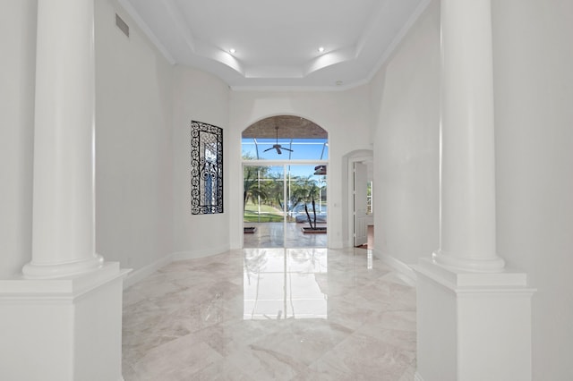 entrance foyer with arched walkways, a tray ceiling, ornate columns, visible vents, and baseboards