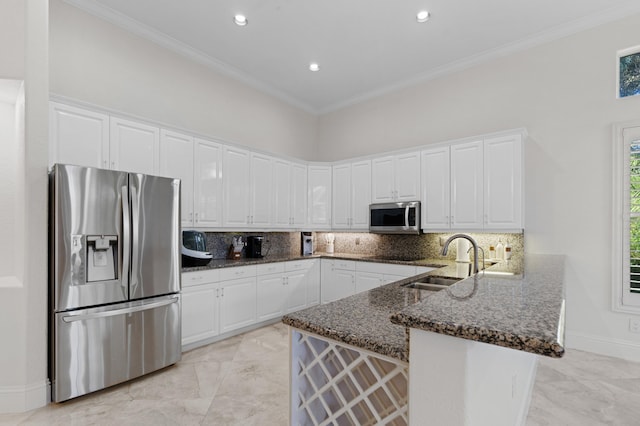 kitchen with marble finish floor, crown molding, appliances with stainless steel finishes, a sink, and a peninsula