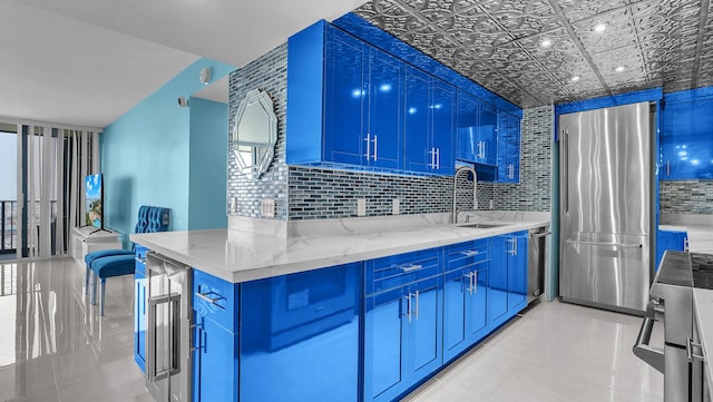 kitchen featuring appliances with stainless steel finishes, sink, backsplash, and light stone counters