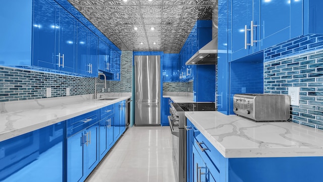 kitchen featuring light stone counters, sink, blue cabinets, and appliances with stainless steel finishes