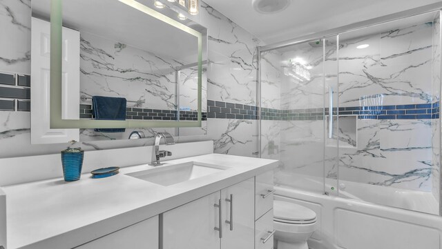 full bathroom featuring bath / shower combo with glass door, vanity, and toilet