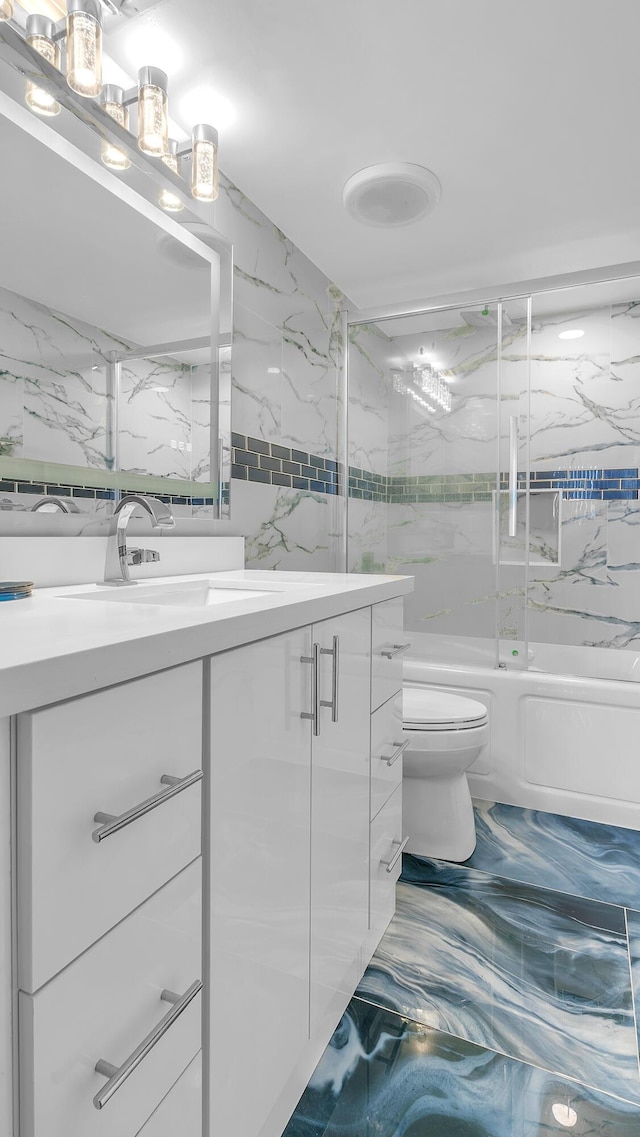 full bathroom featuring vanity, toilet, shower / bath combination with glass door, and tile walls