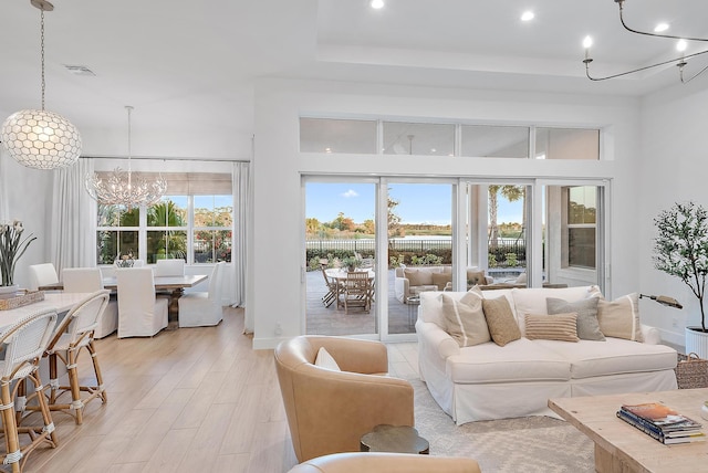 living room featuring a chandelier, light wood-type flooring, and a high ceiling