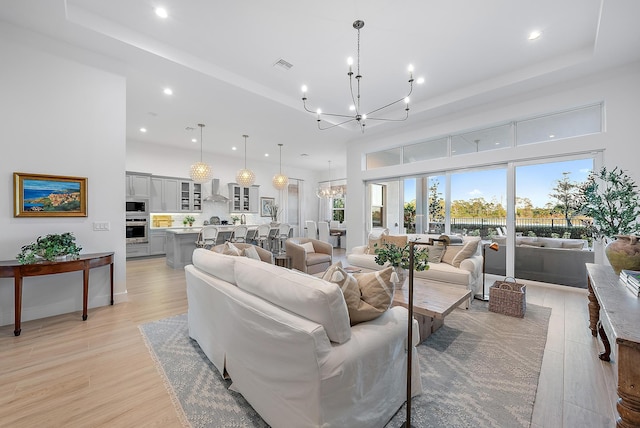 living room with a towering ceiling, a raised ceiling, and a chandelier