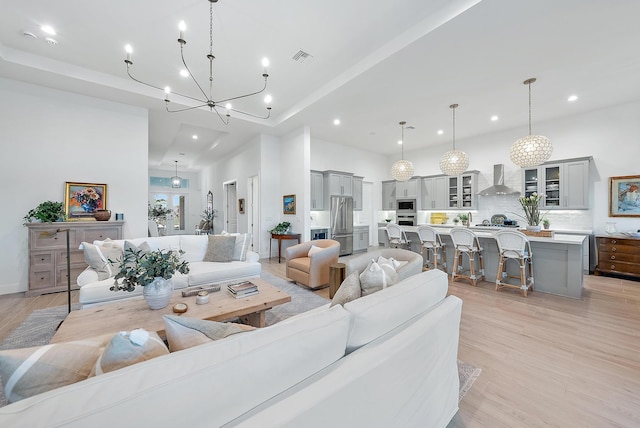 living room featuring a high ceiling, a notable chandelier, and light wood-type flooring