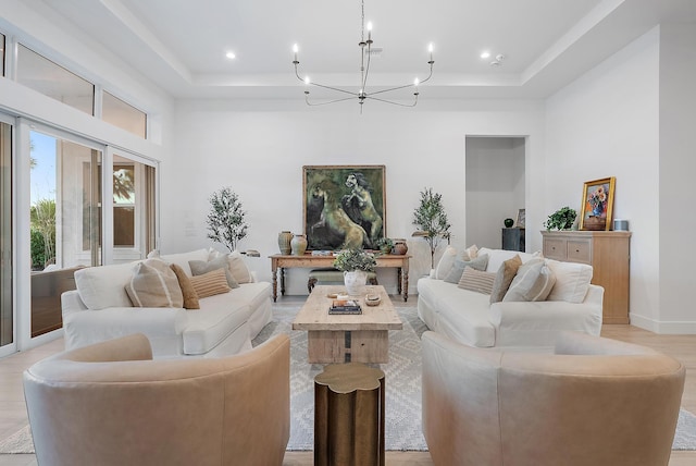 living room with a notable chandelier, light hardwood / wood-style floors, and a tray ceiling