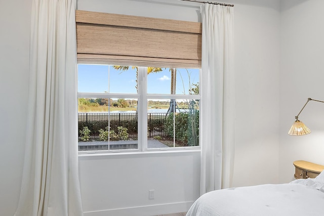 bedroom with a water view and multiple windows