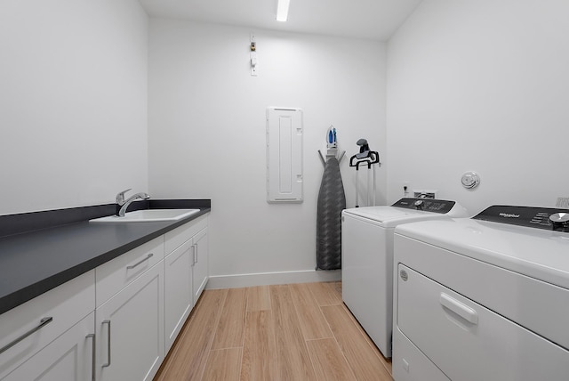 laundry room with sink, washer and clothes dryer, electric panel, cabinets, and light hardwood / wood-style floors