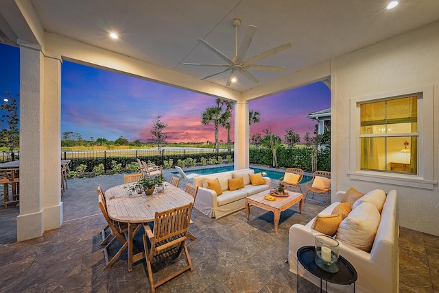 patio terrace at dusk with an outdoor living space, a fenced in pool, and ceiling fan