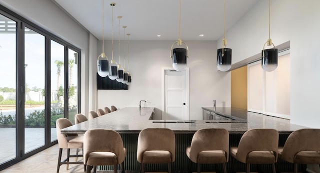 kitchen with a breakfast bar area, hanging light fixtures, kitchen peninsula, dark stone counters, and light parquet floors