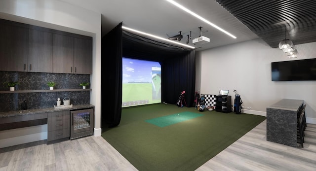 playroom featuring golf simulator, indoor bar, beverage cooler, and light hardwood / wood-style flooring