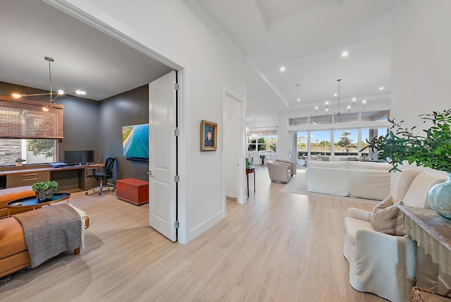 living room with a notable chandelier, a wealth of natural light, and light wood-type flooring