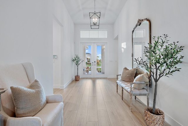 entrance foyer with an inviting chandelier, light hardwood / wood-style floors, and french doors