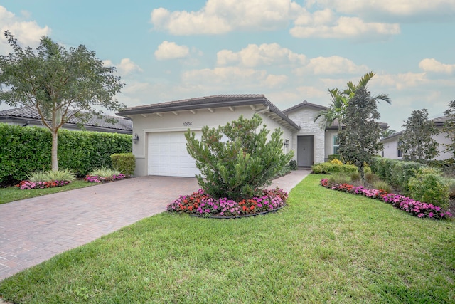 ranch-style house featuring a garage, stone siding, decorative driveway, a front yard, and stucco siding