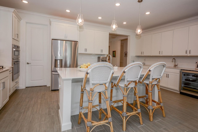 kitchen featuring a center island, light countertops, hanging light fixtures, white cabinetry, and beverage cooler