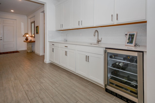 bar with wine cooler, a sink, light wood-style flooring, and tasteful backsplash