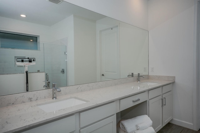 full bath with double vanity, a shower stall, baseboards, and a sink