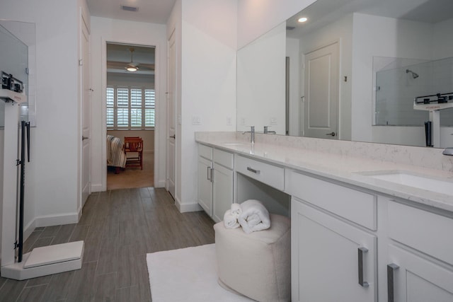 bathroom featuring double vanity, connected bathroom, wood finished floors, a tile shower, and a sink