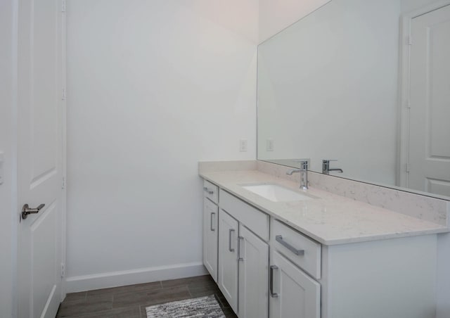 bathroom featuring vanity, baseboards, and wood finished floors